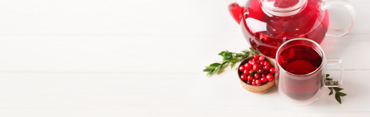 Glass cup of tasty lingonberry tea, pot and fresh berries on white wooden background with space for text