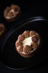 Tarte Schoko-Cheesecake. Feiner Cheesecake mit natürlicher Vanilleschote und einer haube aus Schokolade. Schrarze Hintergrund. 