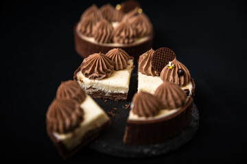 Tarte Schoko-Cheesecake. Feiner Cheesecake mit natürlicher Vanilleschote und einer haube aus Schokolade. Schrarze Hintergrund. 