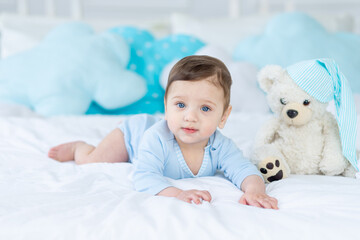 cute baby boy on the bed to sleep with teddy bear, baby room interior, healthy happy little baby