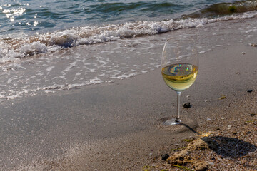 Romantic glass of white wine, on the sea beach. Wine tasting and relaxation at the resort