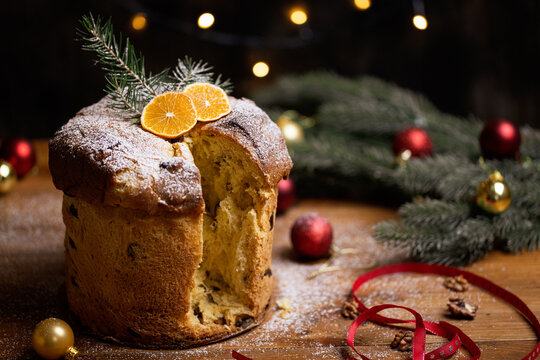 Rustic homemade Christmas traditional Italian holiday panettone cake with festive ribbon, decoration and lights