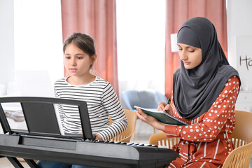 Private Muslim music teacher giving lesson to little girl at home