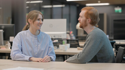 Young Man and Woman having Discussion in Office