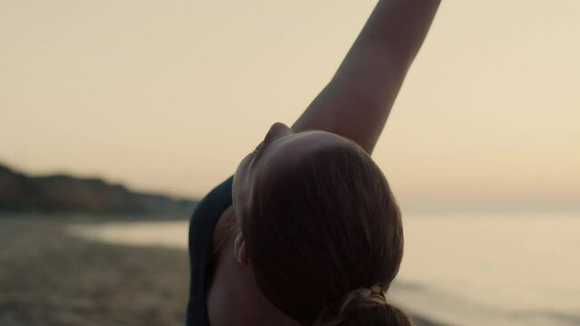 Sportswoman practicing triangl asana on beach close up. Woman training yoga.