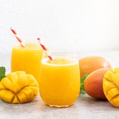 Fresh beautiful delicious mango juice smoothie in a glass cup on gray table background.