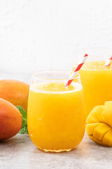 Fresh beautiful delicious mango juice smoothie in a glass cup on gray table background.