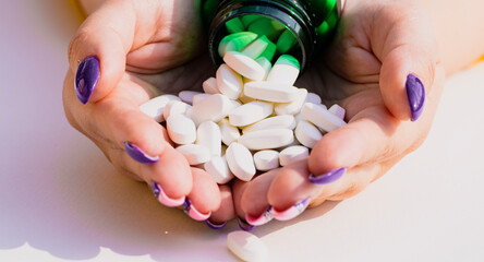 Doctor with pills in hand. Top view of pile of white pills in women's hands