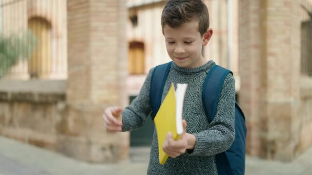 Blond child student hugging book standing at street