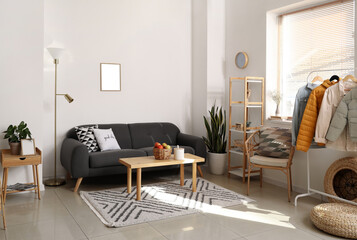 Interior of light room with black sofa and warm jackets