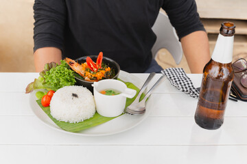 Man eating Thai famous dish pad kra pao stream rice with king prawn on vacation. - obrazy, fototapety, plakaty