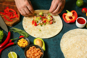 Man preparing tasty burrito with meat on table