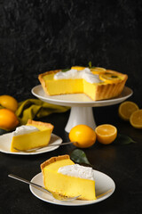Plates with pieces of tasty lemon pie on black background