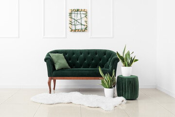New sofa, pouf and houseplants near white wall