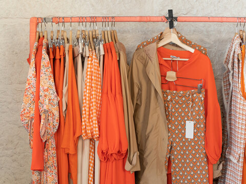 Ropa tonos naranja en perchero de tienda de ropa
