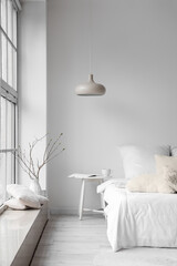 Comfortable bed near white wall in light room interior