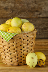 Wicker basket of painted Easter eggs on wooden background