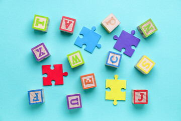 Wooden cubes with letters and puzzle pieces on blue background