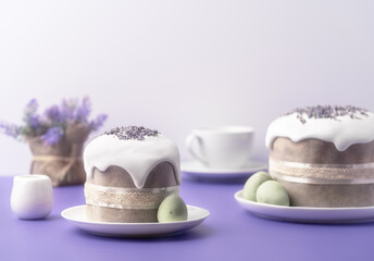 Glazed Easter cakes decorated with lavander flowers and chocolate eggs on bright violet background. Holiday background with copy space for your design.