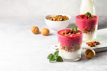 Yogurt, raspberry smoothie and homemade granola in a transparent glass. Healthy breakfast or snack. Copy space