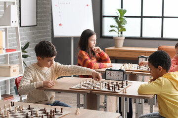 Little children playing chess during tournament in club