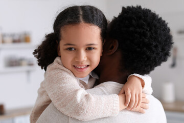 Happy African-American man and his little daughter hugging at home