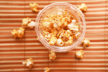  popcorn spilling from a plastic container on wooden background 