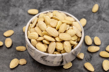 Peeled almond kernel on dark background. A bowl of almonds. close up