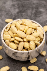 Peeled almond kernel on dark background. A bowl of almonds. close up