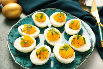 Plate with tasty stuffed eggs on grunge background, closeup. Easter celebration