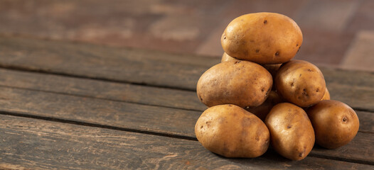 A pile of potatoes on the background of a wooden box. Concept: a bunch of potatoes, vegetable garden, farming, agriculture