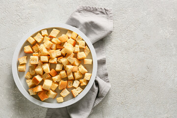 Bowl with tasty croutons and napkin on light background
