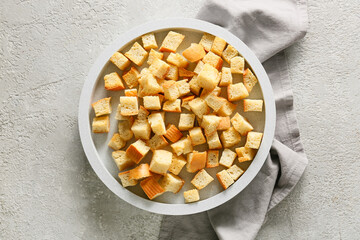 Bowl with tasty croutons and napkin on light background
