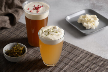 Cheese tea made of green tea and black tea with whipped cream cheese foam topped on grey background. Copy space. Close up.