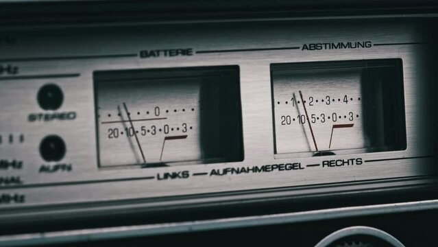 Analog VU meter. Two arrow indicators of signal level on silver-colored tape recorder. Close-up. Analog decibel meters on vintage stereo player. Old dial indicators. Needles on scale classic db meters