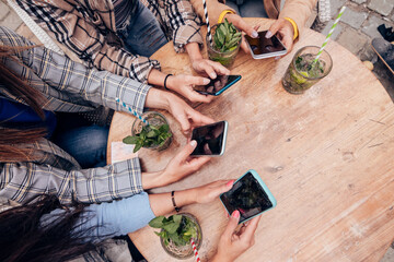 high angle view of a group of female hands using mobile phones at the bar terrace table