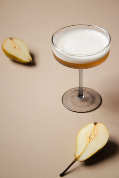 Foamy vegan amaretto sour in a coupe glass and pears around