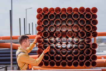 man builder contractor is choosing a sewage pipe from pipes store and preparing for sewer...