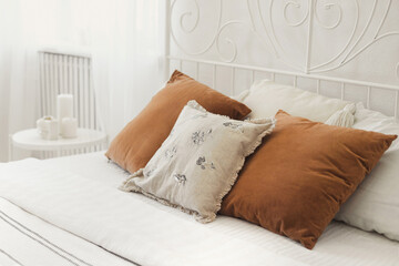 Wrought iron bed with pillows on the bed in cozy bedroom from natural ecological materials linen...
