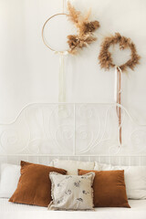 Trendy bedroom with pillows from linen and velvet in beige and brown earth colors and decor from...