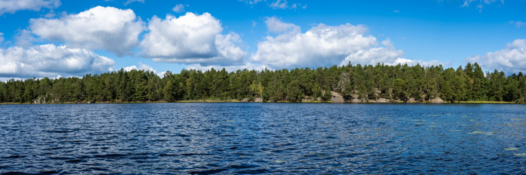 Amazing view of forest shores blue water lake. Scandinavian landscape. Panoramic view Swedish scenery in autumn sunny day. Rocky islands covered with various coniferous trees pines. Banner. Header.