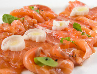 Slices of red fish fillet on a white plate with eggs and herbs.