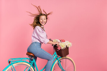 Photo of surprised glad lady drive bike wind blow hair toothy smile wear jacket isolated pink color...