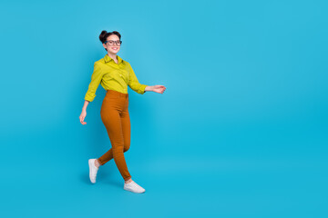 Full length photo of cheerful young person walking empty space isolated on blue color background