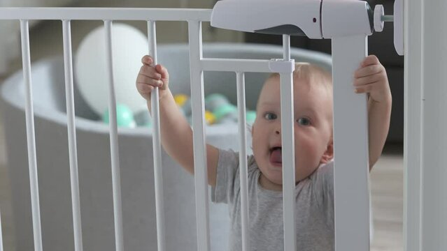 Childproofing a house, doorway with safety baby gates to keep curious kid away from dangerous areas of home, toddler behind bars of closed gate. High quality 4k footage