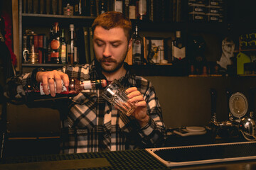 Bartender pouring pomegranate syrup from bottle into highball glass