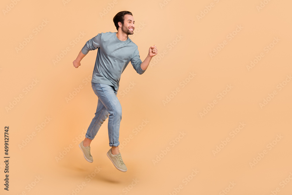 Poster Full size profile side photo of young cheerful guy runner jumper rush fast isolated over beige color background