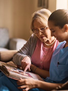 Memory exercises is very important to their health. Shot of a nurse and a senior woman looking at a photo album together.