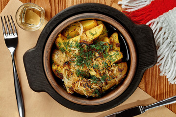 Baked potatoes wedges with fried onion and dill in traditional Georgian clay ketsi