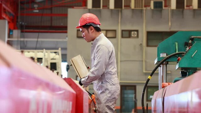 Factory engineer worker operating metal sheet roof machine at Heavy Industry Manufacturing Factory. worker in safety hardhat at factory industrial facilities